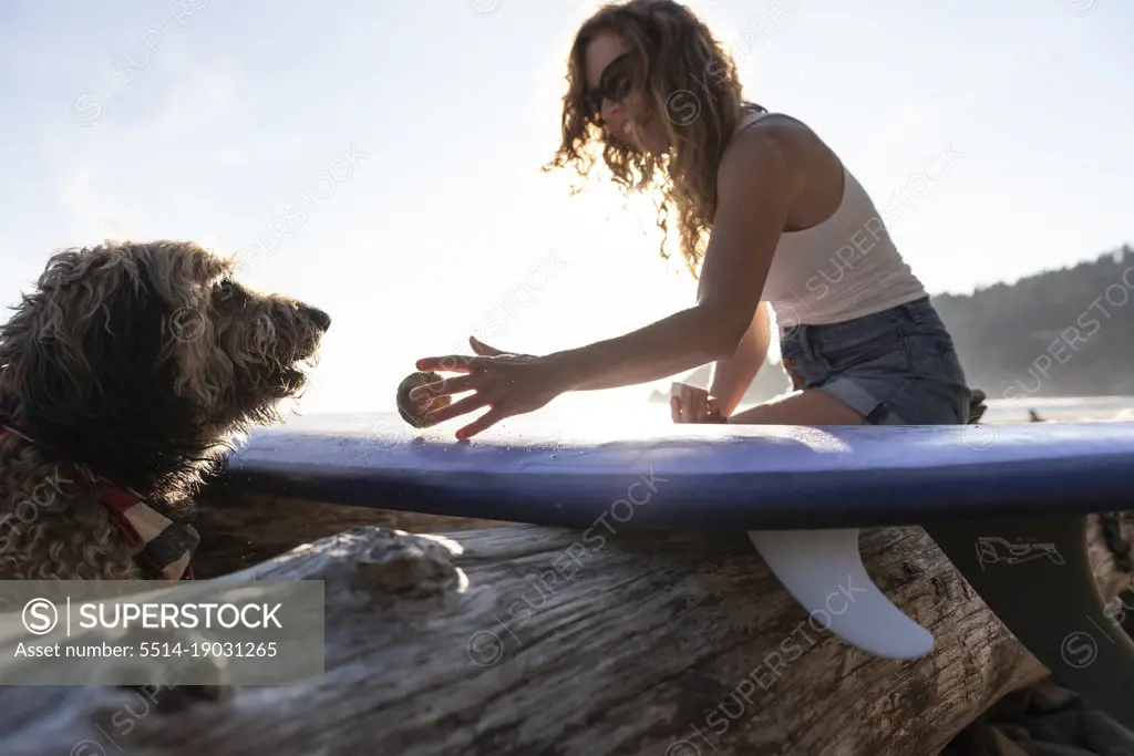 Surfer playing ball with her dog on the Oregon coast