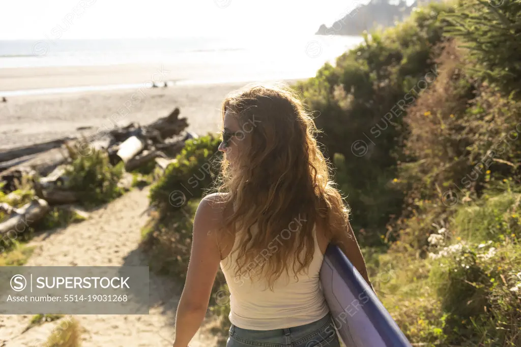 Woman carrying surboard down the beach along the Oregon coast