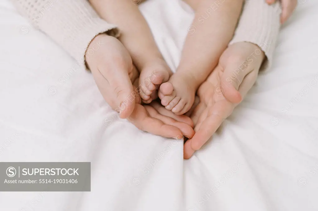 mother holding her baby daughter's feet in her hands