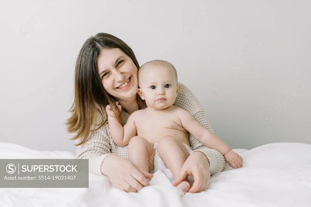 young mother with her young baby daughter on bed