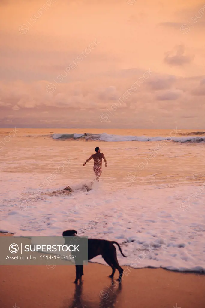 boy running in to the ocean during the sunset on the pacific