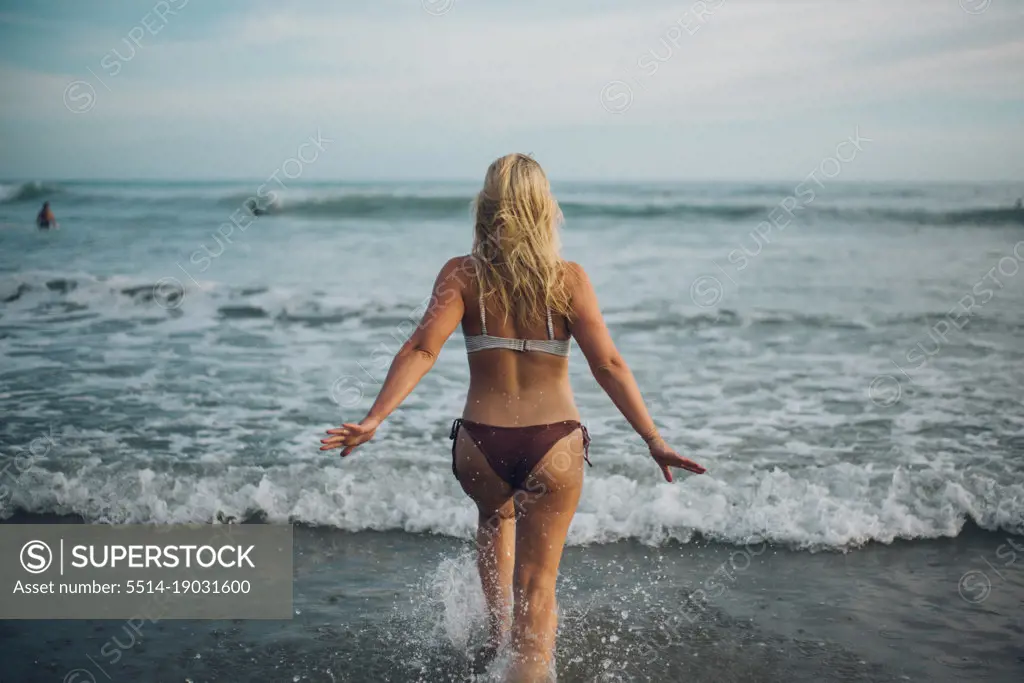 back portrait of a surfer girl going in to the sea