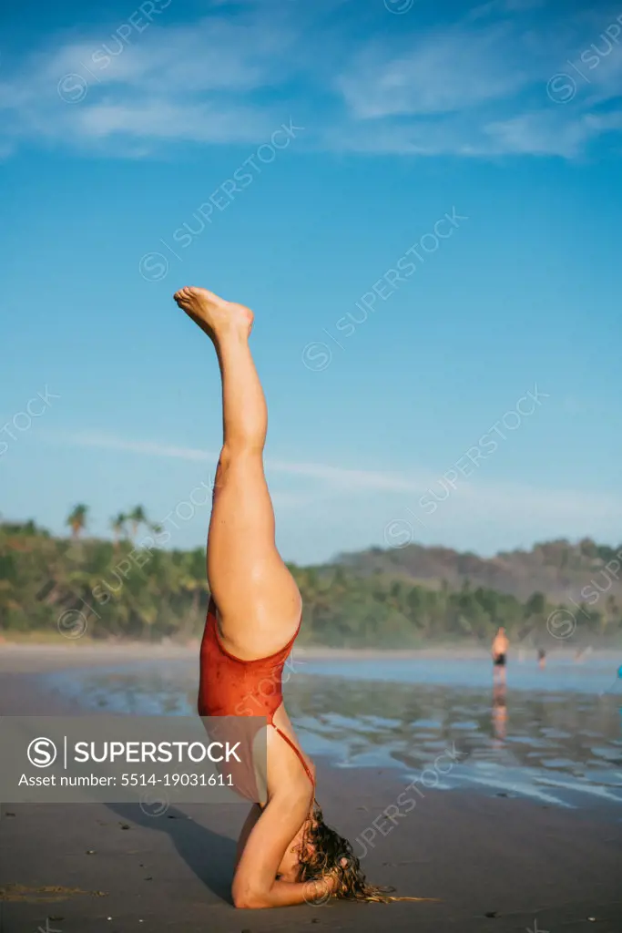 healty blond girl making a yoga pose on the beach