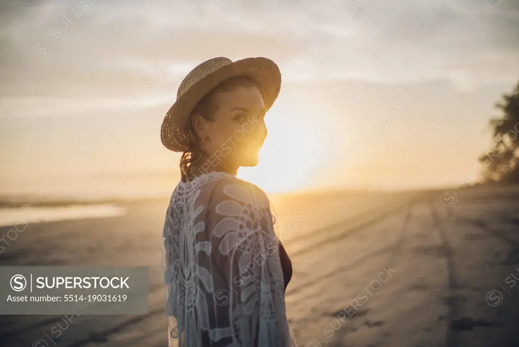 backlighting portrait of a blond girl wearing a hat on the beach