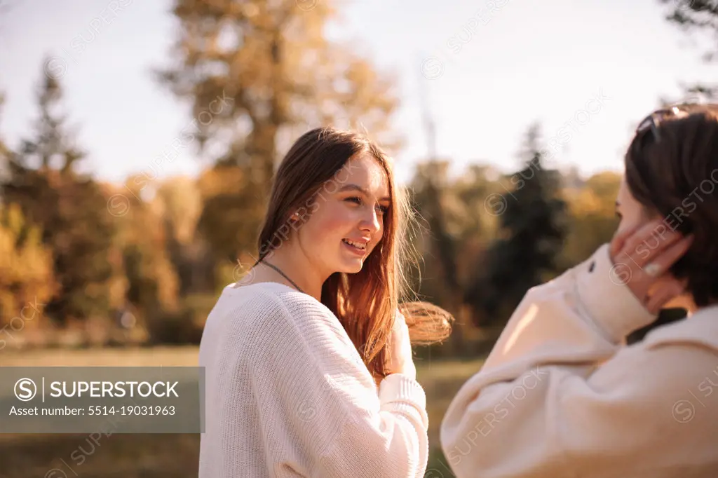 Happy young woman looking at her girlfriend while standing in park