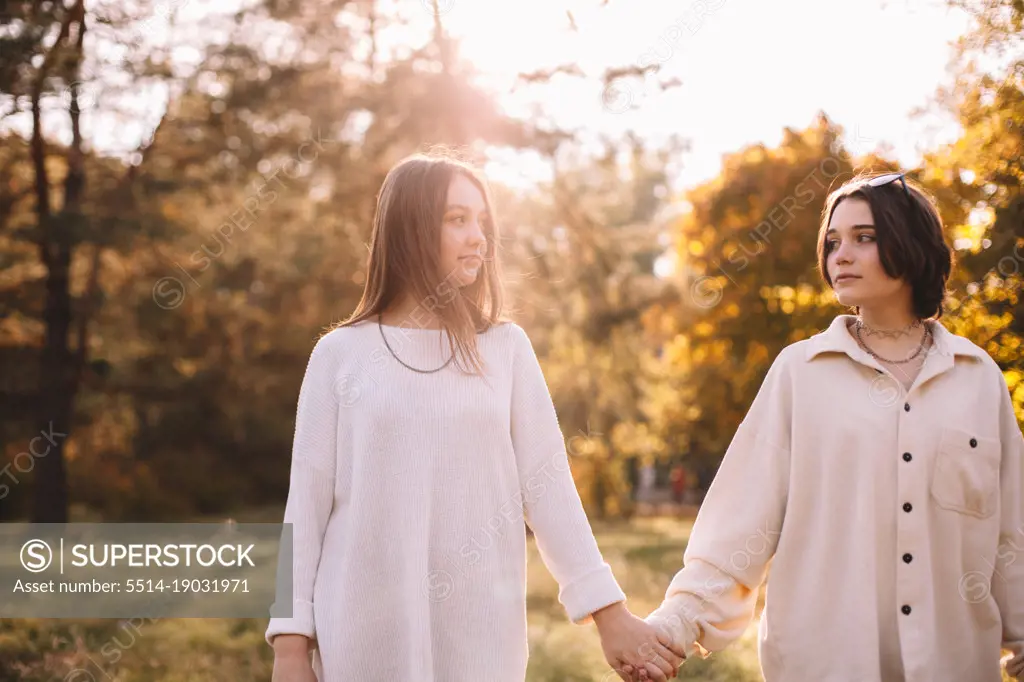 Lesbian couple holding hands while standing in park during autumn