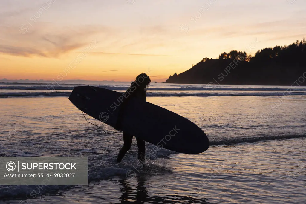 Silhouette of person carrying surfboard at Short Sands, Oregon