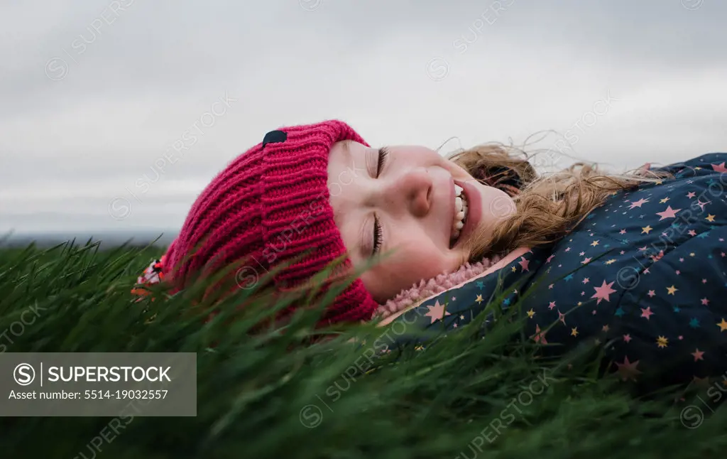 child laying in green grass happily breathing in fresh air