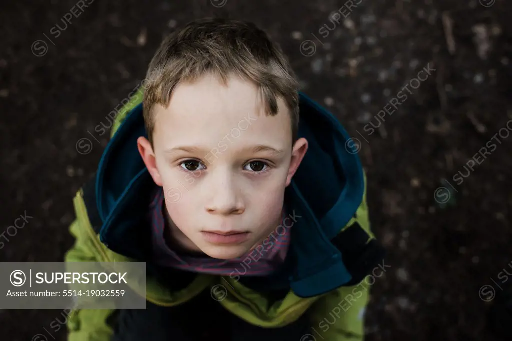 portrait of a serious brown eyed boy looking up