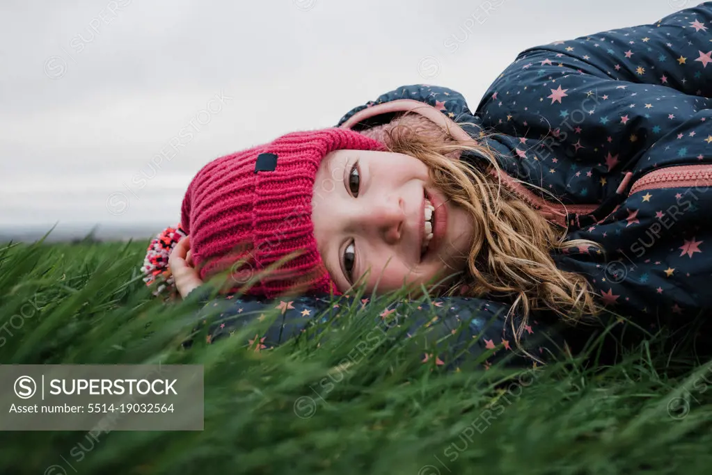 girl laying in the grass smiling at one with nature