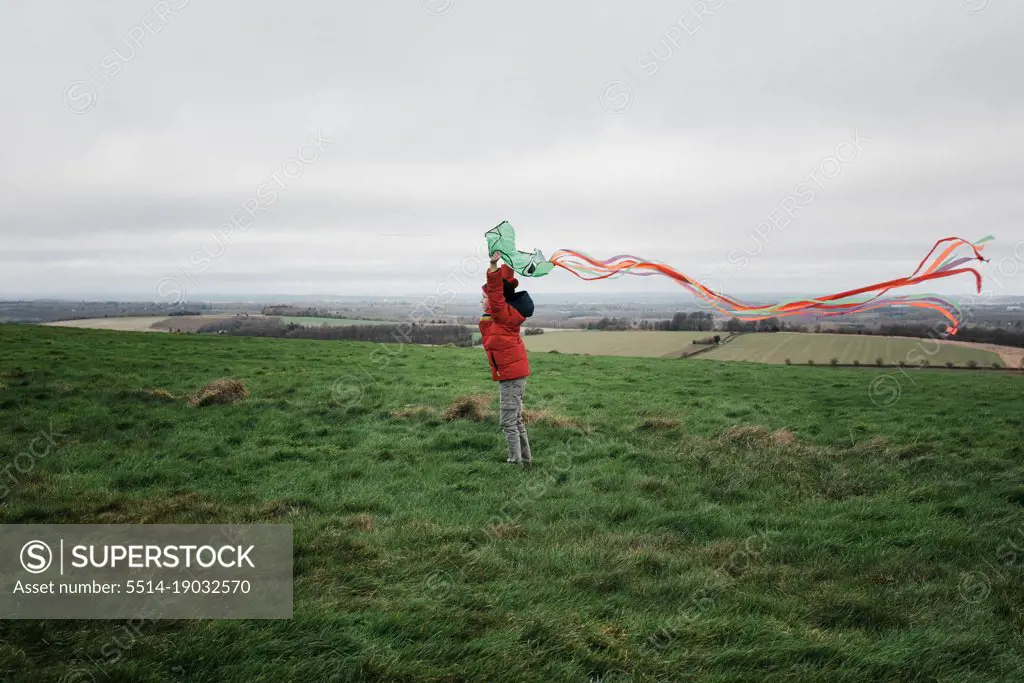 boy flying a kite in a windy field in winter