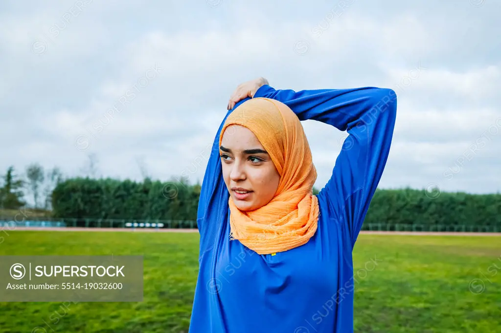 Muslim ethnic woman warming up sports field