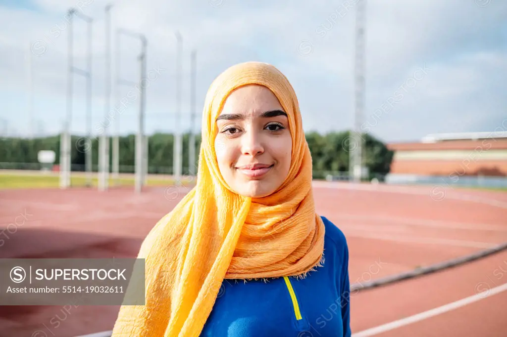 Charming ethnic woman in hijab on running track