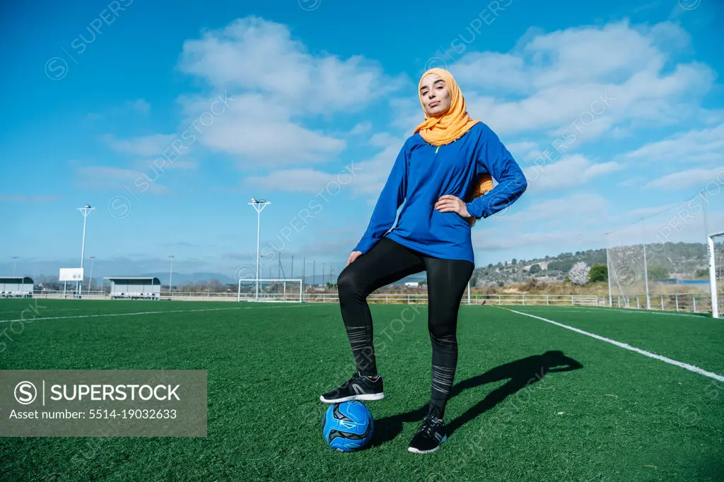 Arab female football player with ball on field