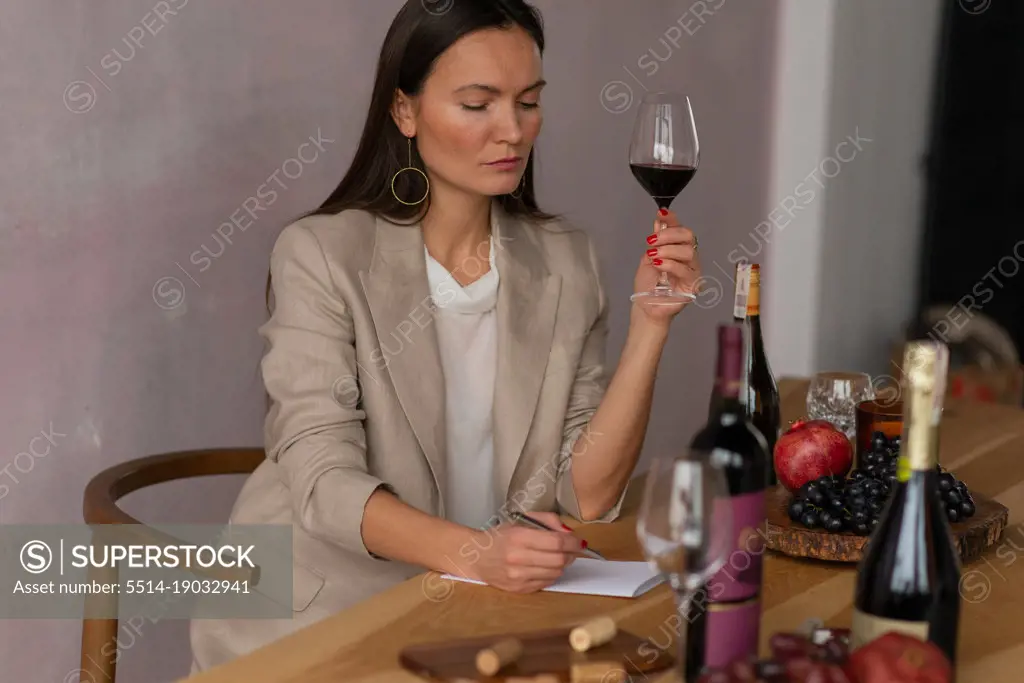 Sommelier woman writing notes testing wine in glass