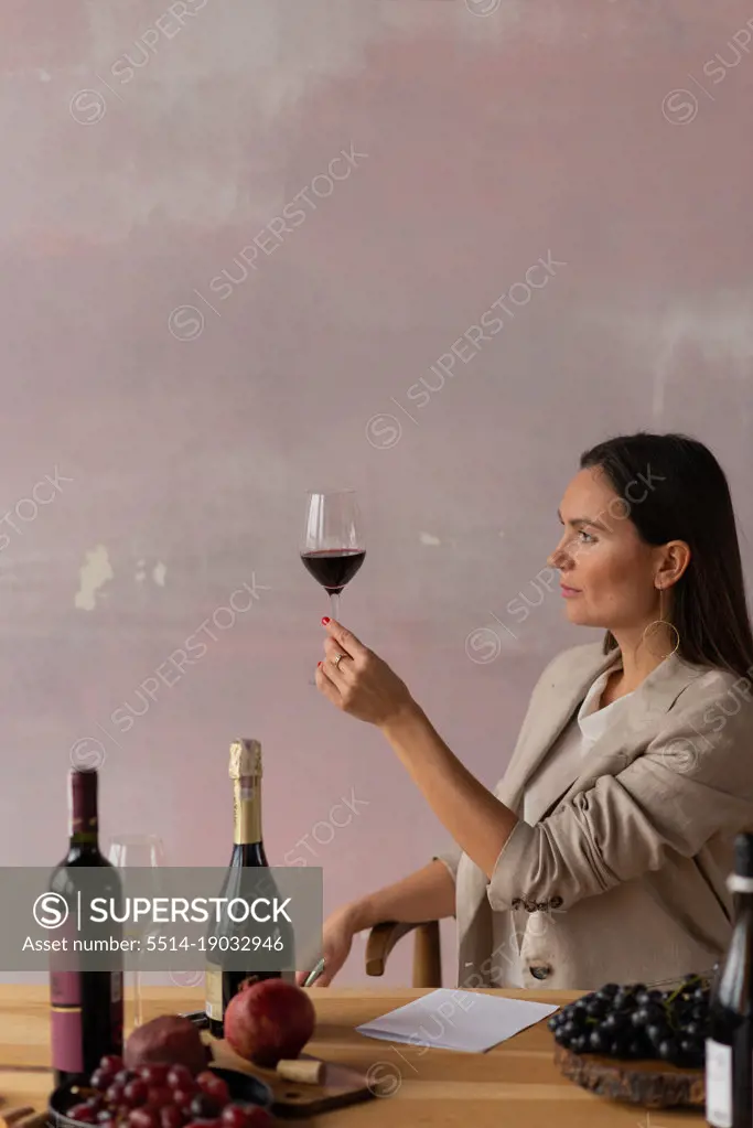 Female sommelier looking at color of wine in glass, making degustation