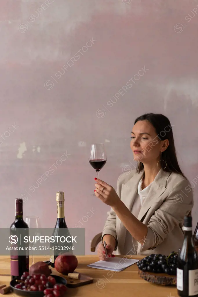 Brunette woman sommelier writing notes testing wine drink