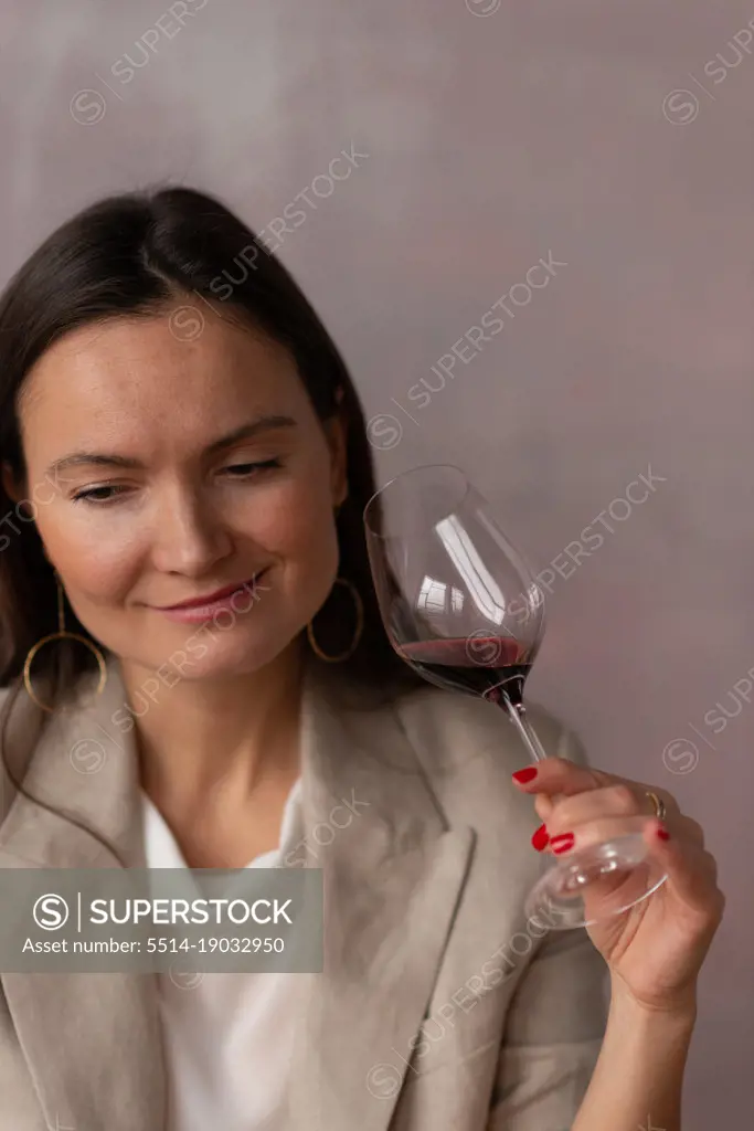 Smiling woman with glass of wine on pink studio background
