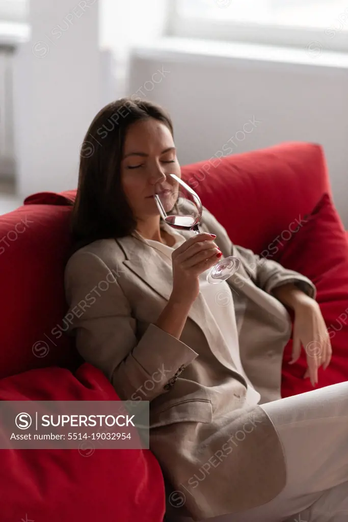 Beautiful brunette woman smelling wine from glass