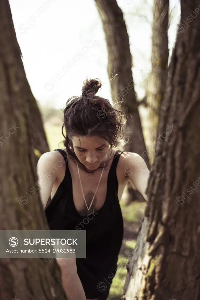 natural woman with face paint and freckles climbs tree in german natur