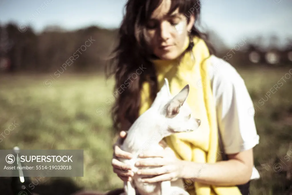 Small white dog sitting on young alternative face painted woman