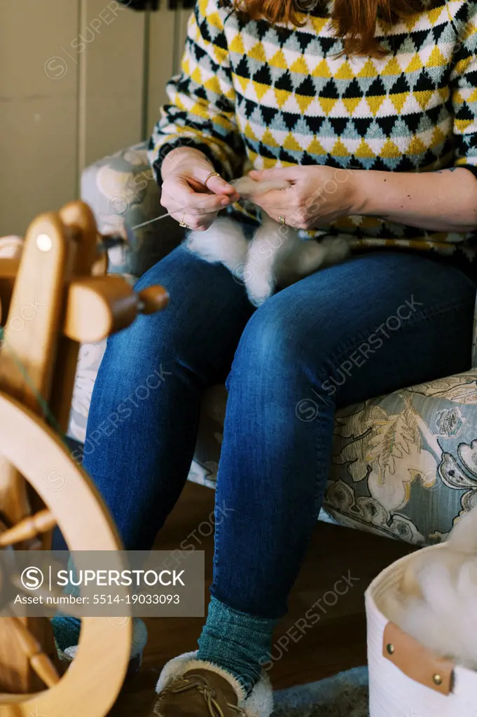 millennial woman spinning wool into yarn in her living room