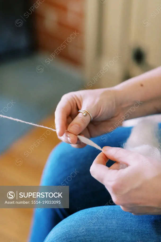 millennial woman spinning wool into yarn in her living room