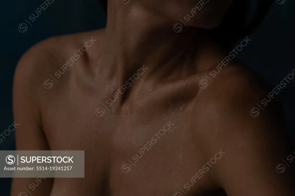 Woman neck and breast in little water drops in darkness - SuperStock