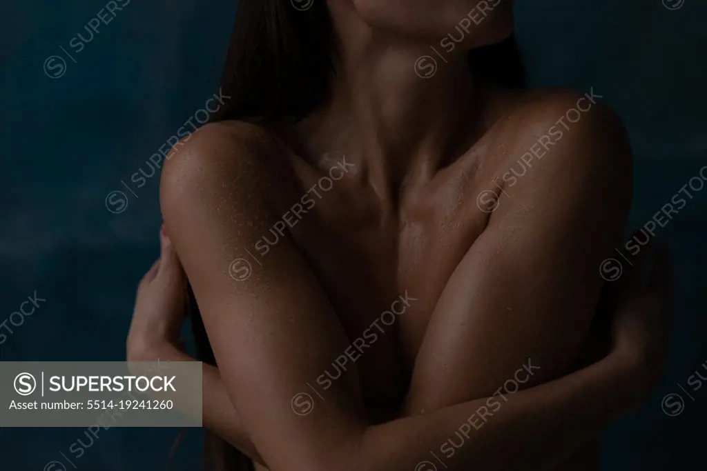 Close up woman in water drops  embracing herself by hands