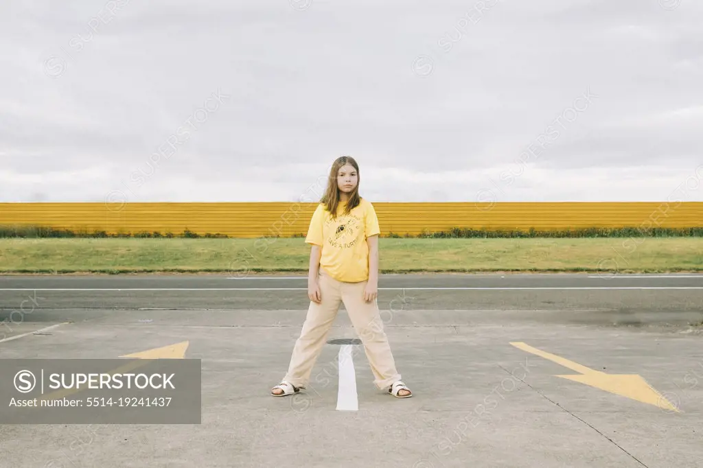Young girl standing alone in a car park