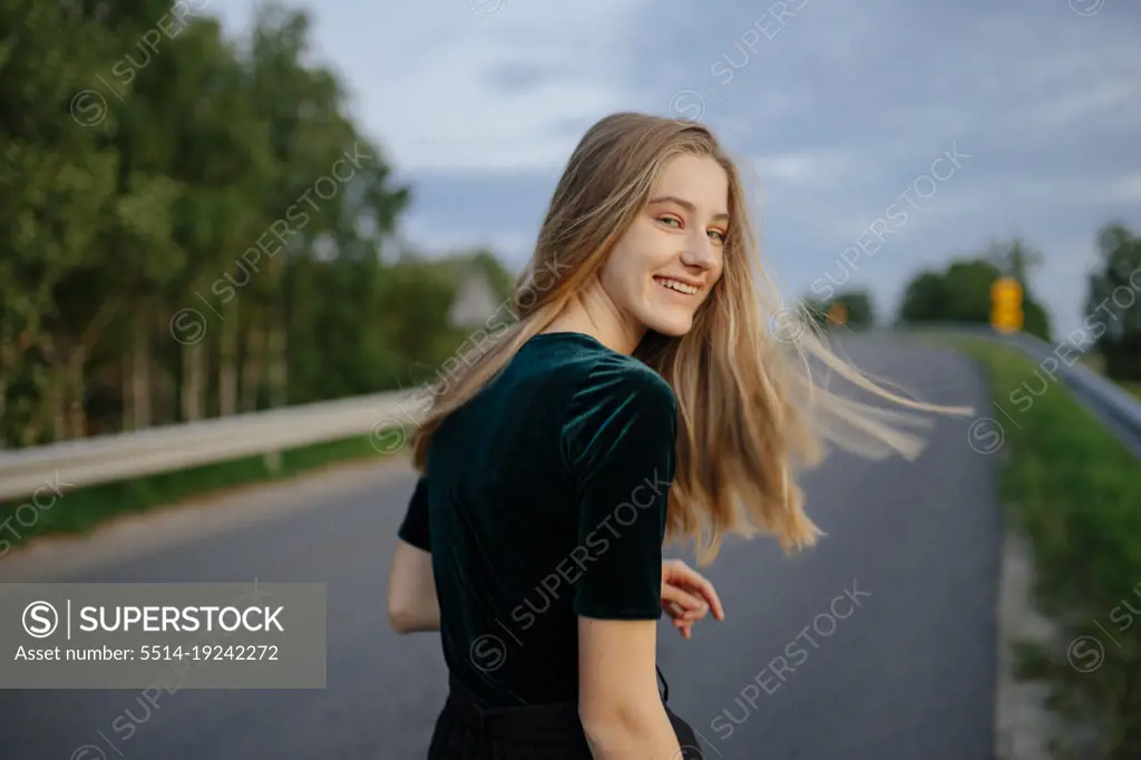 Woman walking down the road turning around smiling
