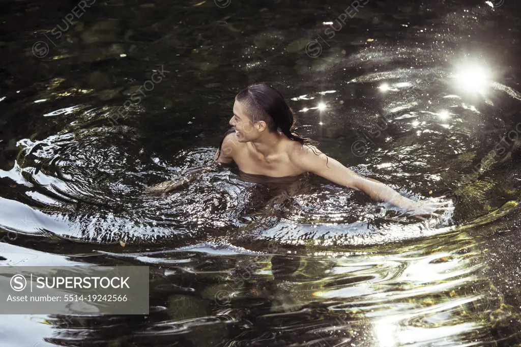 Androgynous young person wading in luscious water