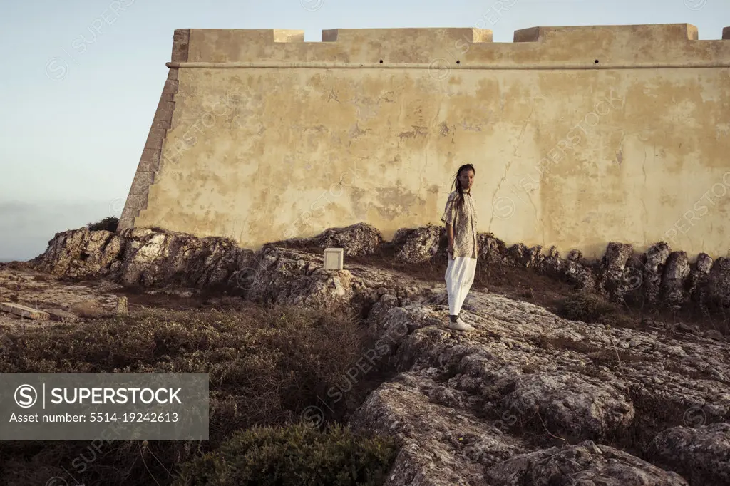 androgynous person stands in front of historic fort in Portugal