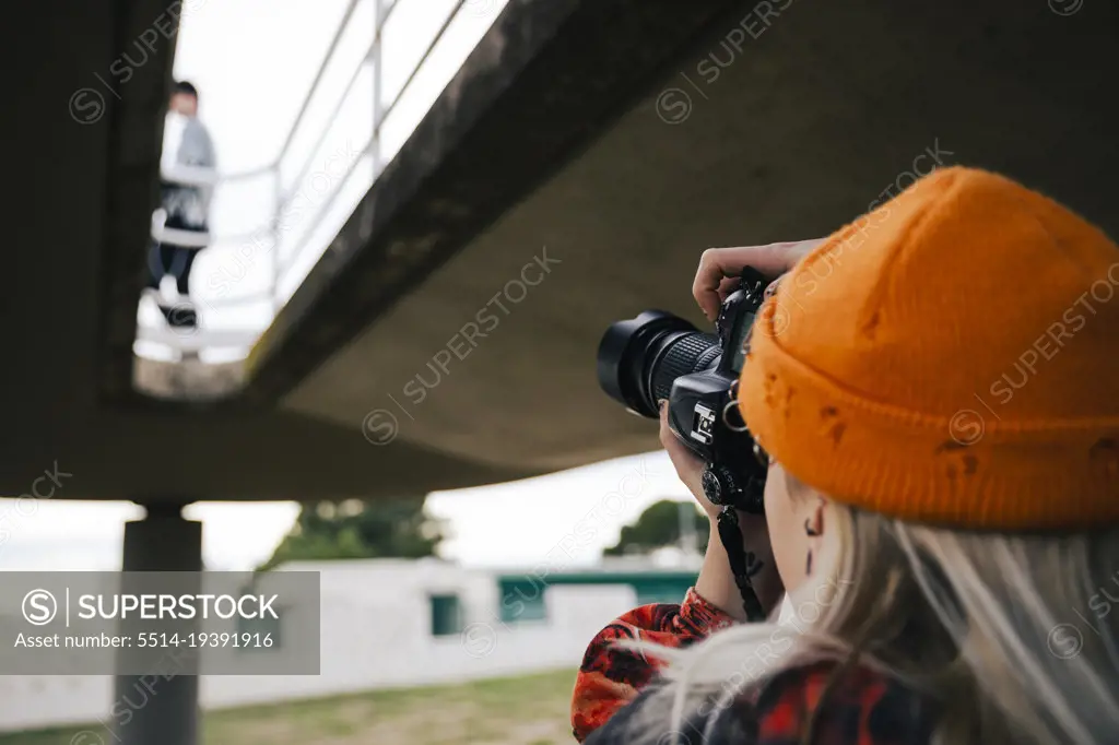 Photographer with a hat taking photos with his camera outdoors
