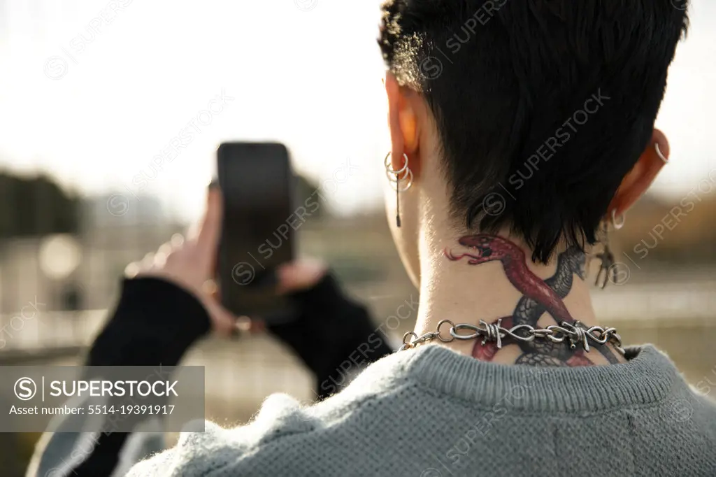 Unrecognizable girl with a tattoo taking a picture