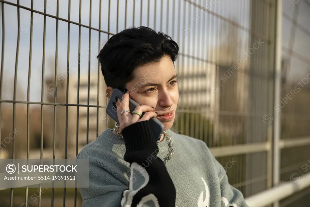Lesbian girl talking on her smartphone while smiling outdoors