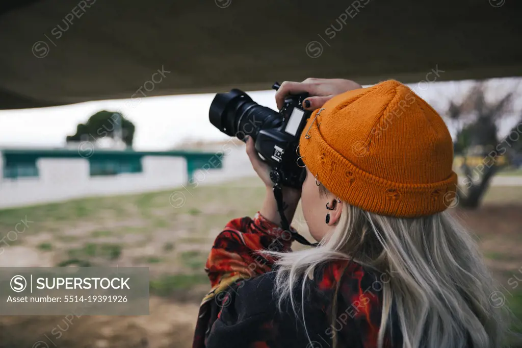 Photographer with a hat taking photos with his camera outdoors