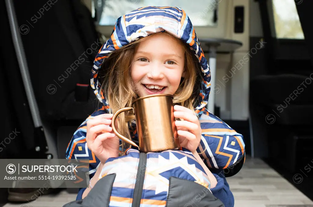child drinking hot chocolate happily in a campervan on holiday