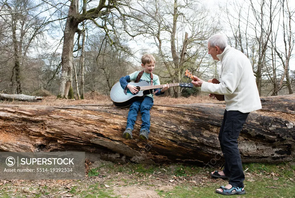 grandfather teaching his grandson how to play guitar on vacation
