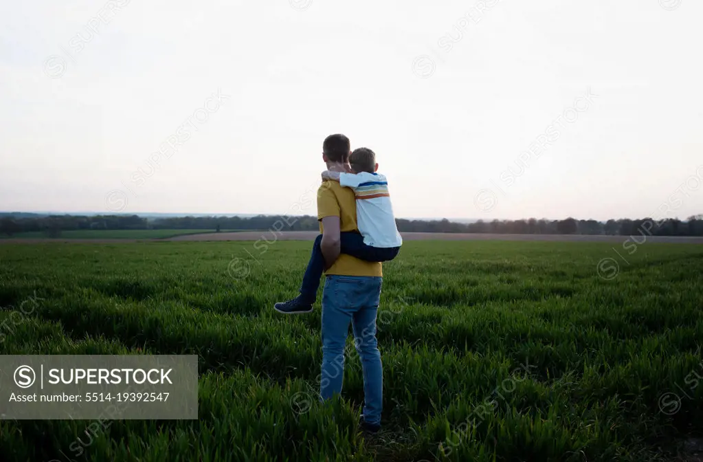 father giving his son a piggyback whilst walking in the countryside