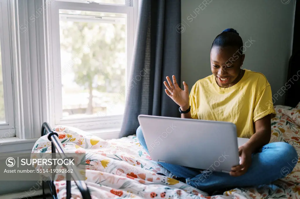 Young black girl waving at screen during video chat