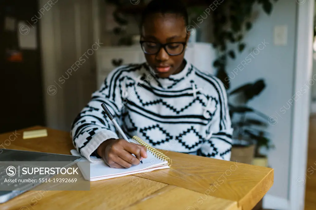 Young black teen girl doing homework at dining room table
