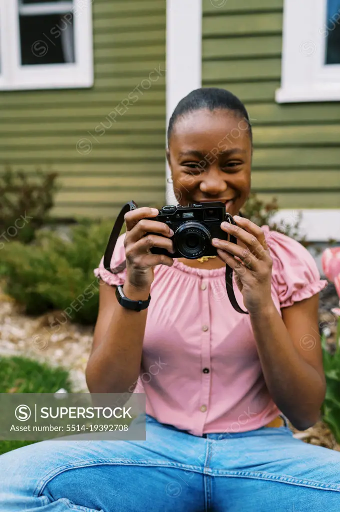 teenage girl sitting in her yard with her compact camera
