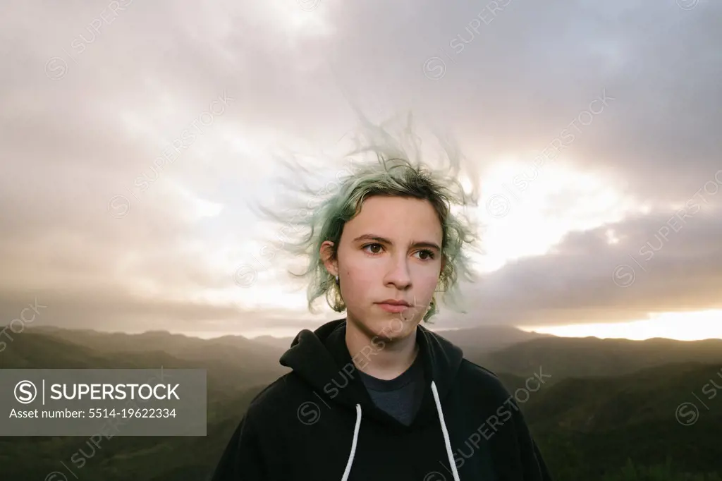 Serious Teen Girl On Top Of A Mountain During Sunset