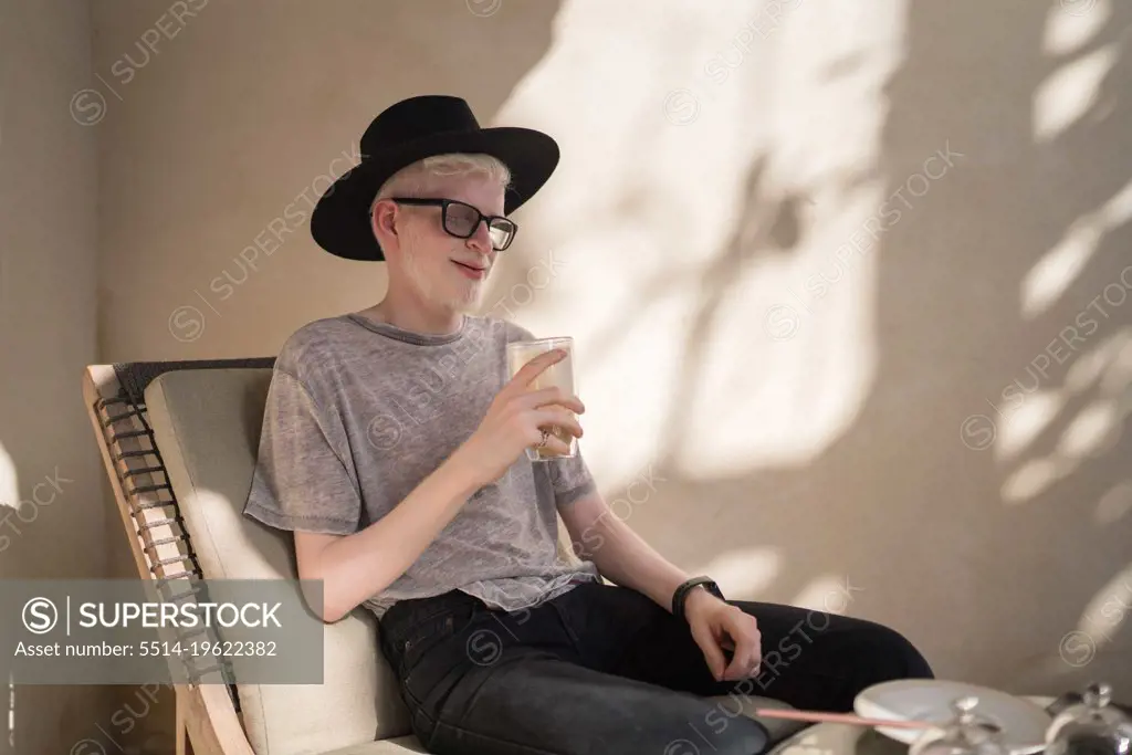 Albino man sitting at the outdoor cafe drinking coffee