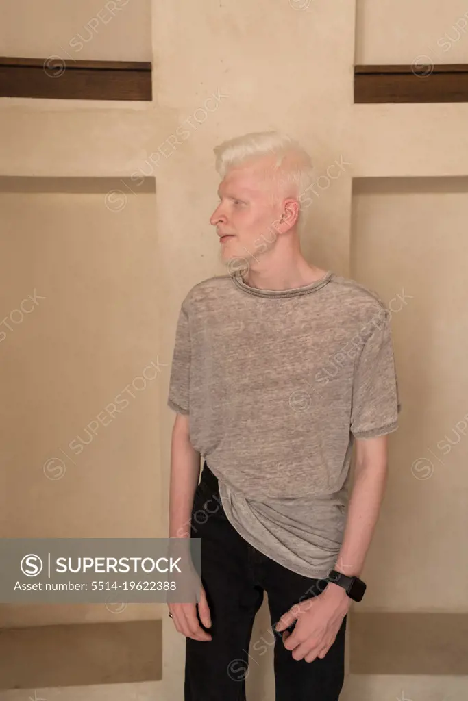Albino man wearing hat portrait standing by the wall