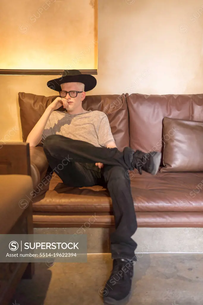 Albino man portrait sitting on the leather couch looking at the camera