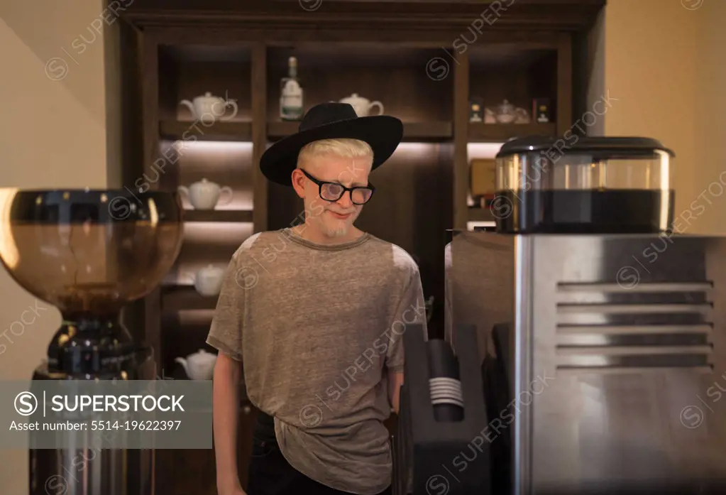 Albino man wearing a hat barista making coffee at the cafe