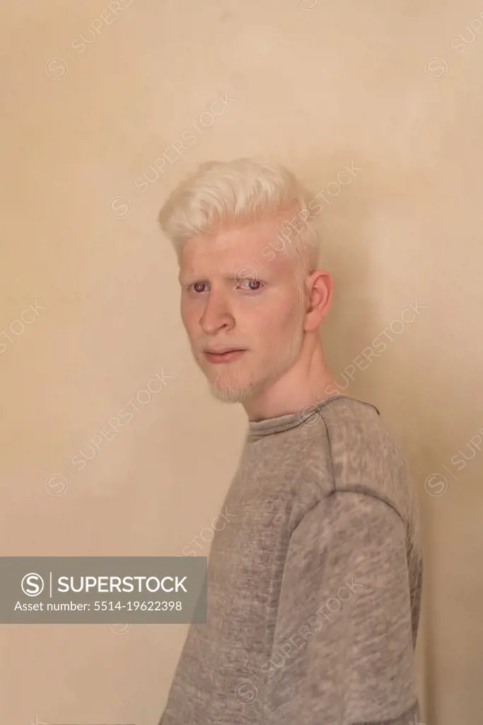 Albino man standing by the wall portrait