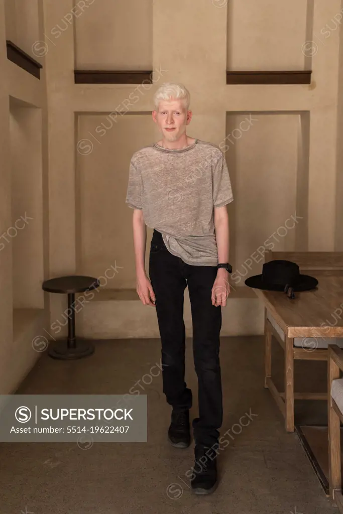 Albino man standing by the wall full length  portrait